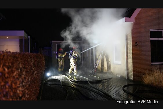 Fikse brand in spouwmuur van woning. Brandweer slaat stenen uit muur om te blussen