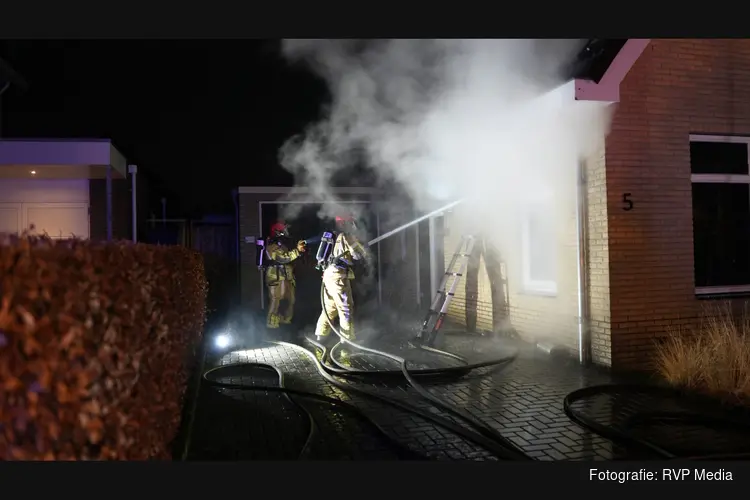 Fikse brand in spouwmuur van woning. Brandweer slaat stenen uit muur om te blussen